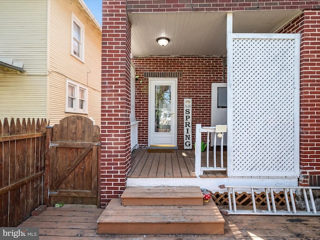 property entrance featuring a gate, brick siding, and fence