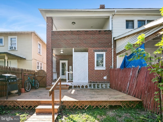 back of house featuring a wooden deck, brick siding, and fence private yard
