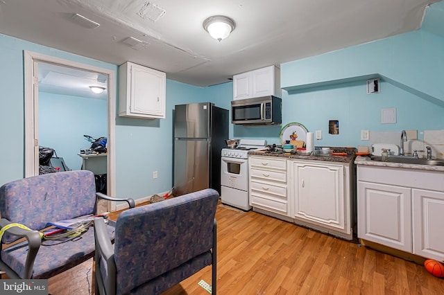 kitchen with a sink, white cabinets, light wood-style floors, and stainless steel appliances