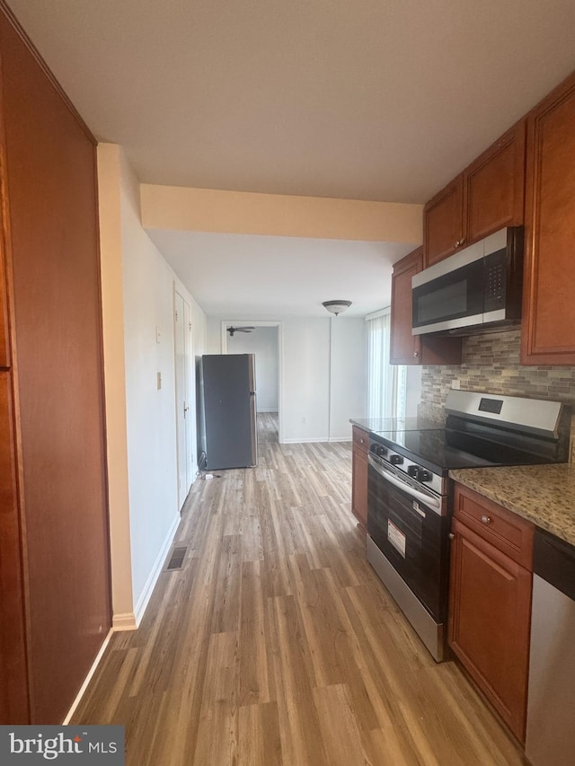 kitchen with brown cabinets, visible vents, light wood-type flooring, and appliances with stainless steel finishes