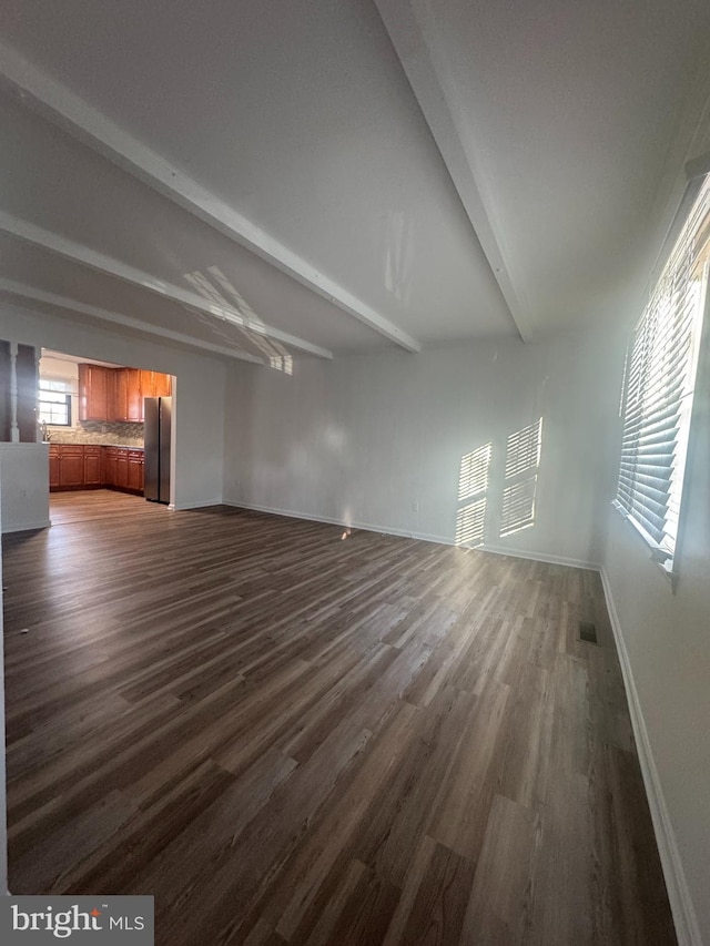 unfurnished living room with beamed ceiling, baseboards, dark wood finished floors, and visible vents