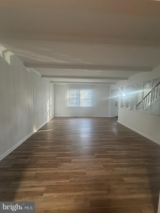spare room with stairs, baseboards, beamed ceiling, and wood finished floors