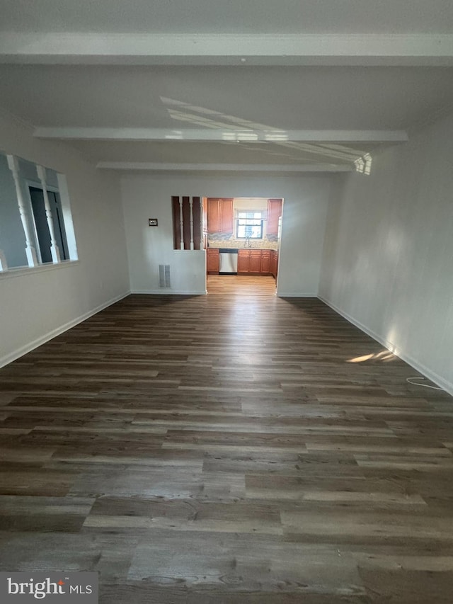 empty room with beamed ceiling, baseboards, visible vents, and dark wood-style floors