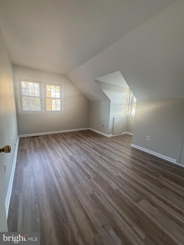 bonus room with baseboards, lofted ceiling, and dark wood finished floors