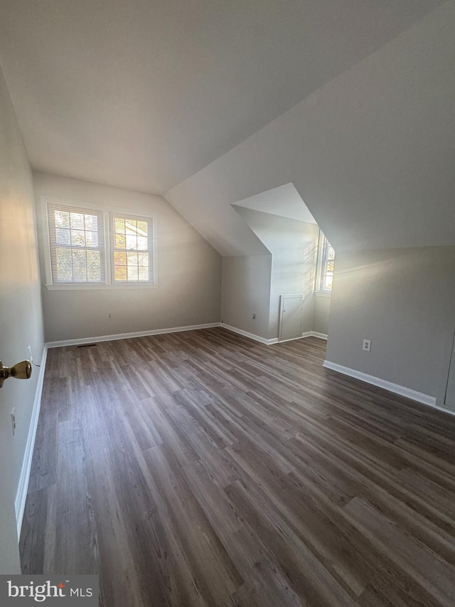 additional living space with lofted ceiling, baseboards, and dark wood finished floors