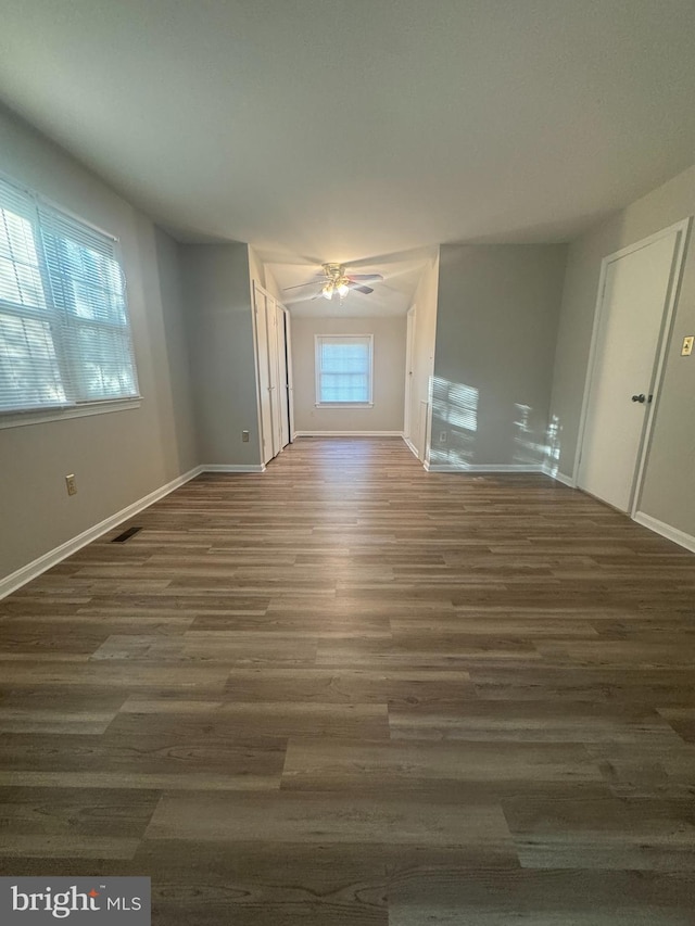 empty room with visible vents, baseboards, a ceiling fan, and wood finished floors