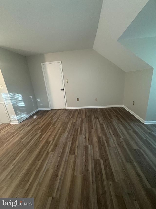 additional living space with dark wood-style flooring, baseboards, and lofted ceiling