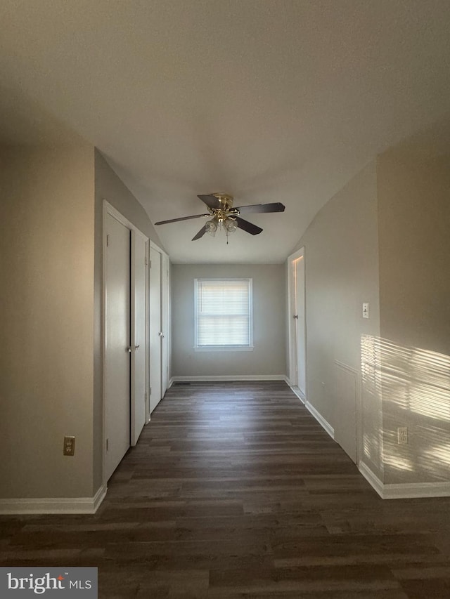 interior space featuring a closet, dark wood-type flooring, baseboards, and a ceiling fan