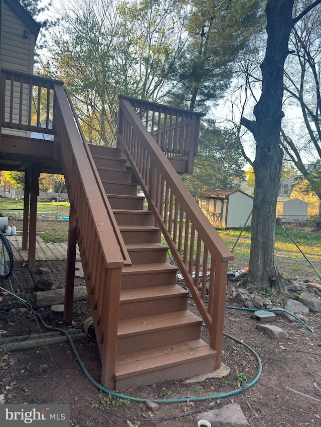 deck with a storage shed, an outdoor structure, and stairs