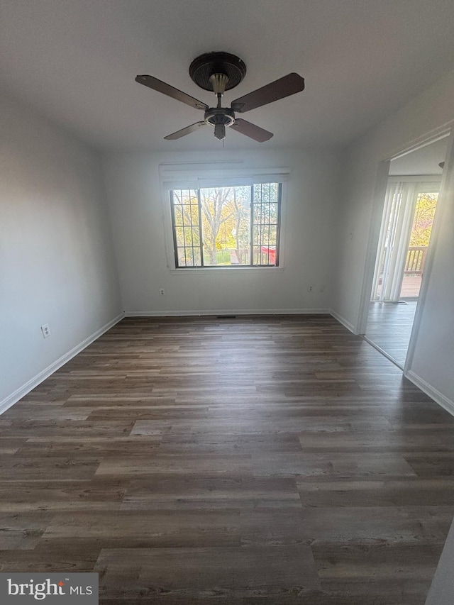 unfurnished room with baseboards, a ceiling fan, and dark wood-style floors