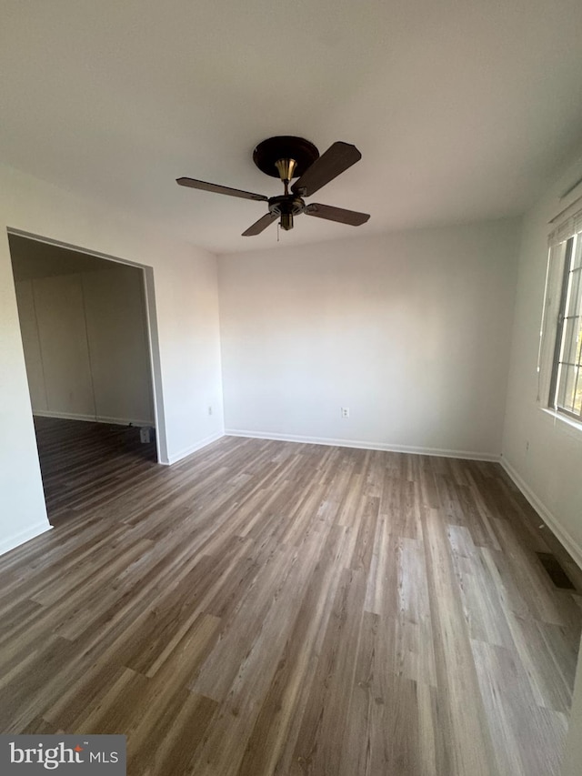interior space with wood finished floors, baseboards, a ceiling fan, and visible vents