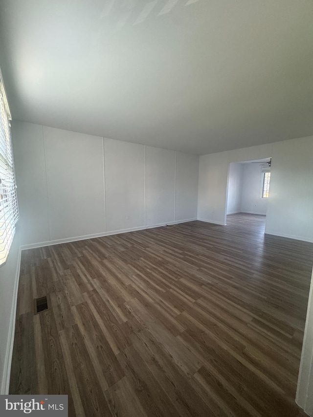 empty room with baseboards, dark wood-style floors, and visible vents