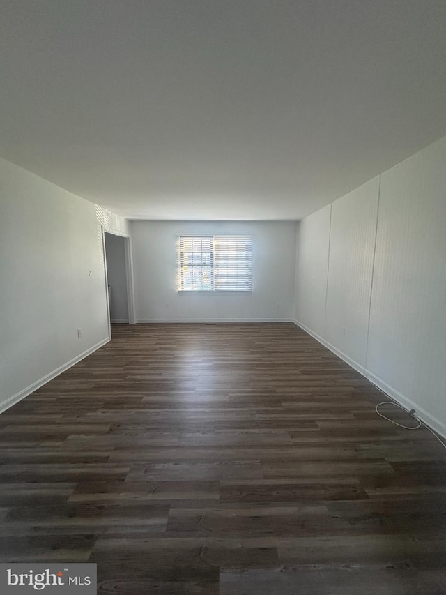 unfurnished room featuring baseboards and dark wood finished floors
