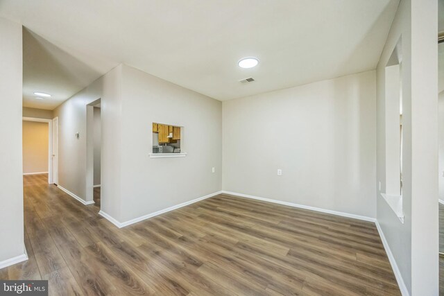 empty room featuring baseboards, visible vents, and wood finished floors