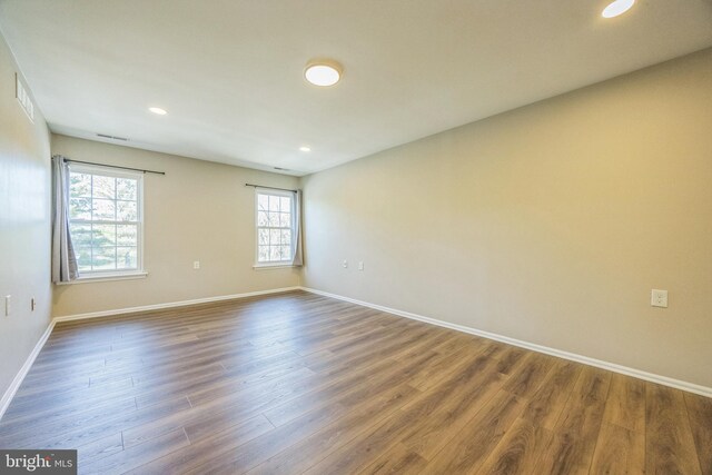empty room featuring baseboards, recessed lighting, wood finished floors, and visible vents
