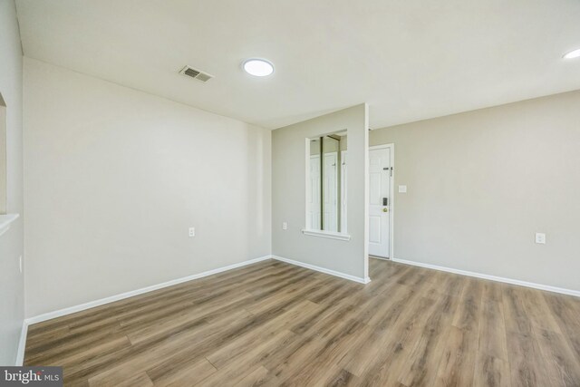 empty room with visible vents, recessed lighting, baseboards, and wood finished floors