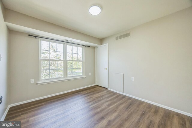empty room with visible vents, baseboards, and wood finished floors