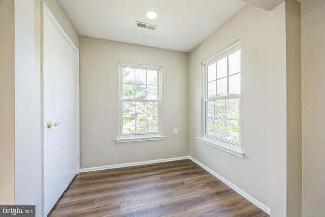 empty room with baseboards, visible vents, and wood finished floors