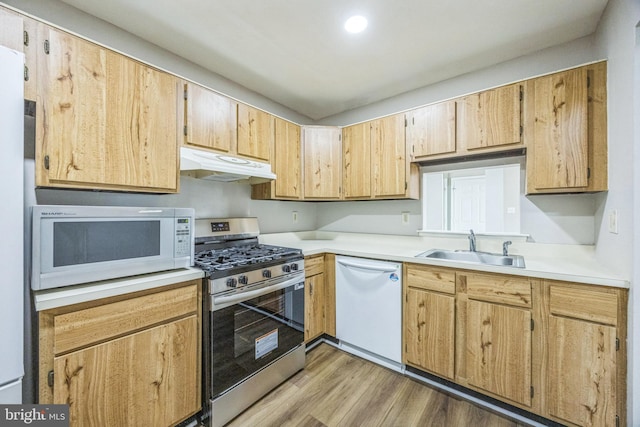 kitchen featuring white appliances, light wood-type flooring, light countertops, under cabinet range hood, and a sink