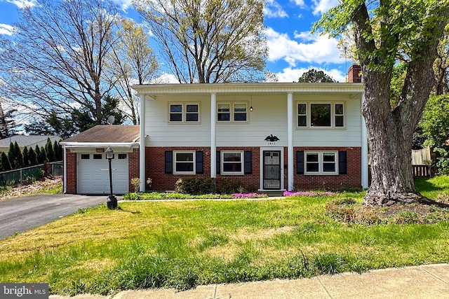 greek revival house featuring brick siding, an attached garage, aphalt driveway, and fence