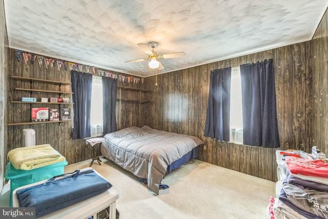 carpeted bedroom with wood walls, a textured ceiling, and ceiling fan