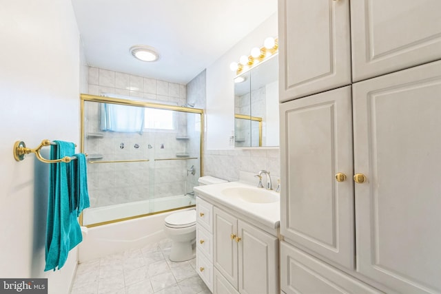 full bath with toilet, vanity, combined bath / shower with glass door, and tile walls