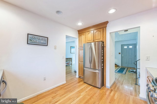 kitchen featuring range, light wood-style floors, freestanding refrigerator, and baseboards