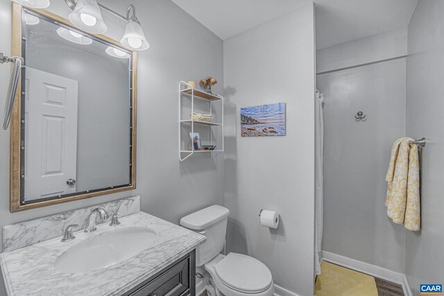 bathroom with toilet, vanity, a shower with curtain, and baseboards