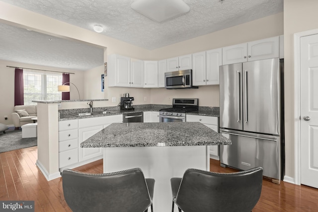 kitchen with a textured ceiling, white cabinetry, appliances with stainless steel finishes, and a sink