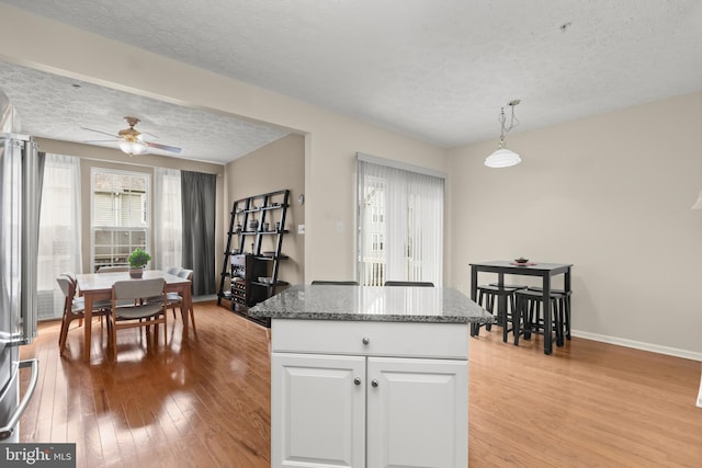 kitchen with a ceiling fan, pendant lighting, white cabinetry, a textured ceiling, and light wood-type flooring