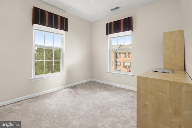 carpeted spare room featuring visible vents and baseboards