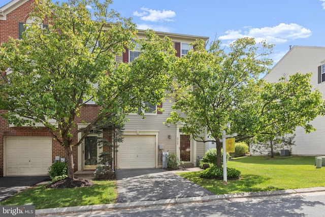 view of front facade featuring aphalt driveway, a garage, brick siding, and a front yard