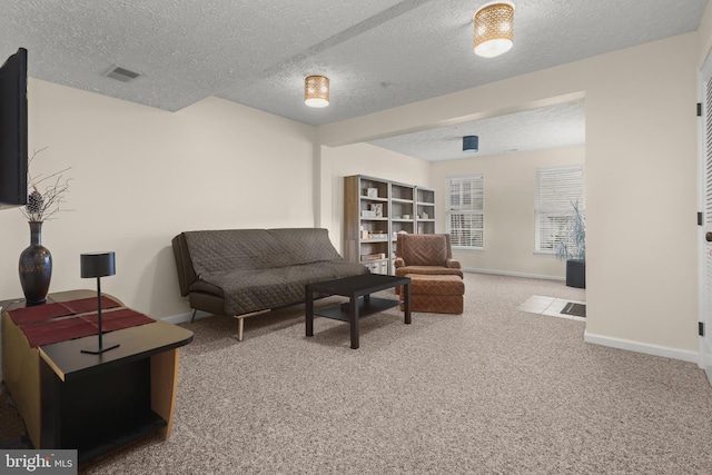 sitting room with a textured ceiling, carpet, baseboards, and visible vents