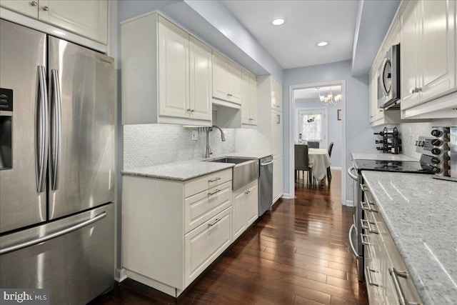 kitchen featuring a sink, dark wood finished floors, backsplash, light stone countertops, and appliances with stainless steel finishes