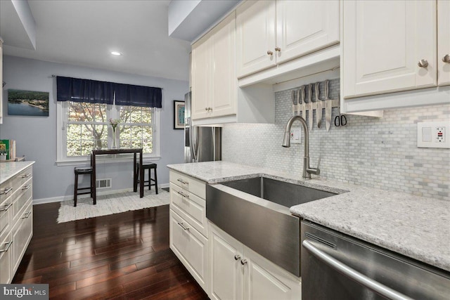 kitchen featuring dark wood finished floors, stainless steel appliances, a sink, baseboards, and tasteful backsplash