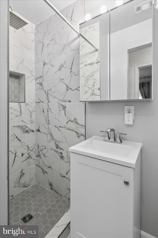 bathroom with a marble finish shower, vanity, and visible vents