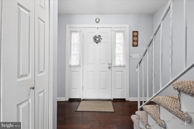 foyer entrance with baseboards, wood finished floors, and stairs