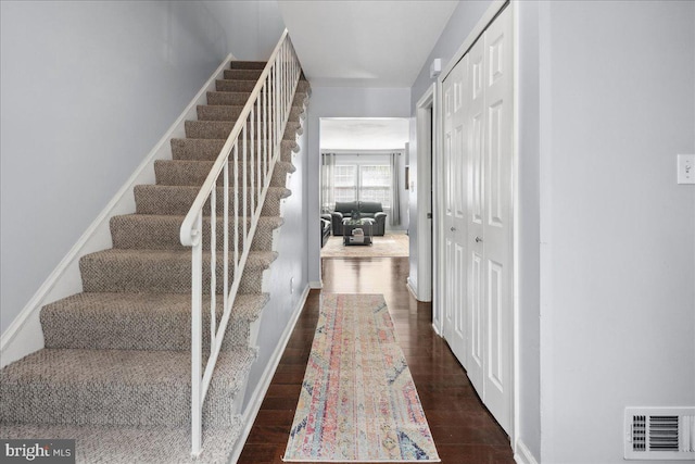 staircase featuring baseboards, wood finished floors, and visible vents