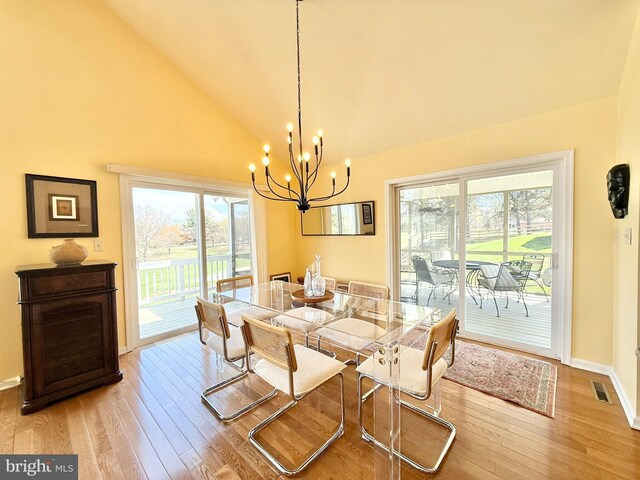 477 Wampum Ln, Hedgesville, WV 25427 - dining area with light wood finished floors, high vaulted ceiling, a chandelier, baseboards, and visible vents