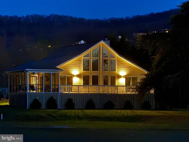 477 Wampum Ln, Hedgesville, WV 25427 - back of house at night with a sunroom, a yard, and a chimney