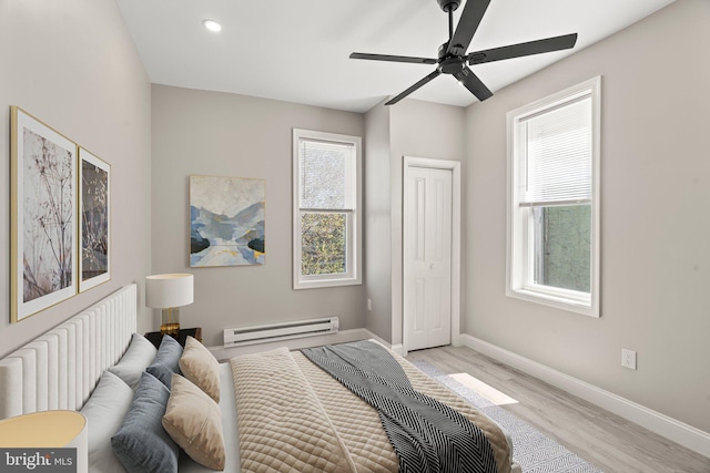 bedroom featuring baseboard heating, a closet, baseboards, recessed lighting, and light wood-style flooring