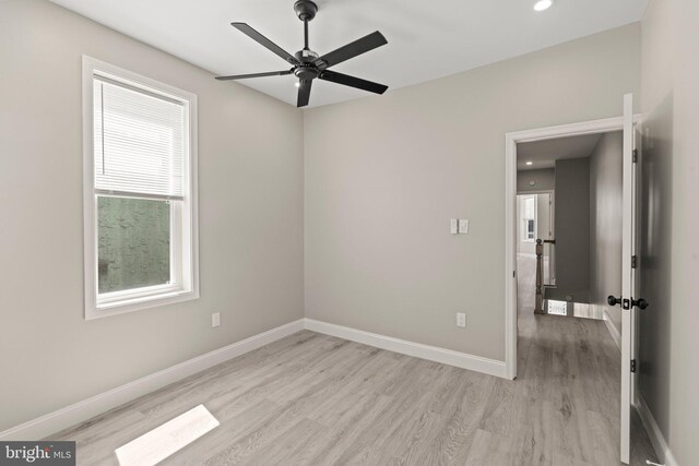 empty room featuring ceiling fan, light wood-type flooring, and baseboards