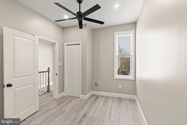 unfurnished bedroom featuring light wood-style flooring, a closet, baseboards, and visible vents