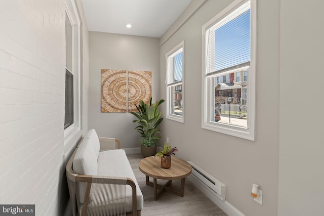 living area with baseboard heating, wood finished floors, baseboards, and recessed lighting