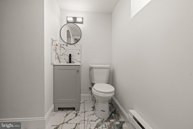 half bathroom featuring vanity, a baseboard heating unit, baseboards, toilet, and marble finish floor