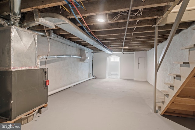 below grade area with electric panel, stairs, and heating unit