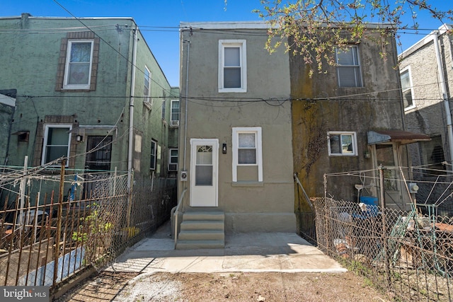 view of front of house featuring entry steps, stucco siding, and fence