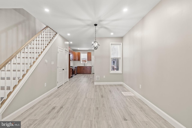unfurnished living room with recessed lighting, stairs, light wood-style flooring, and baseboards
