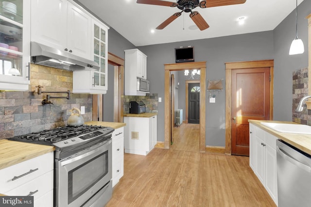 kitchen featuring wooden counters, a sink, stainless steel appliances, and under cabinet range hood