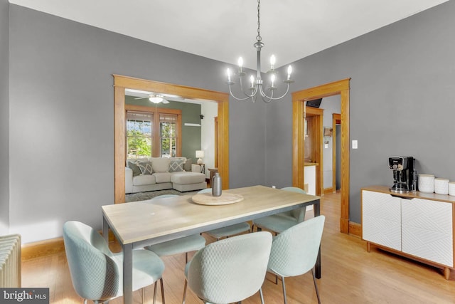 dining area featuring radiator heating unit, light wood finished floors, ceiling fan with notable chandelier, and baseboards
